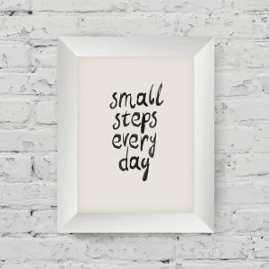 Motivational poster "small steps every day" in the art wooden frame on on white brick wall